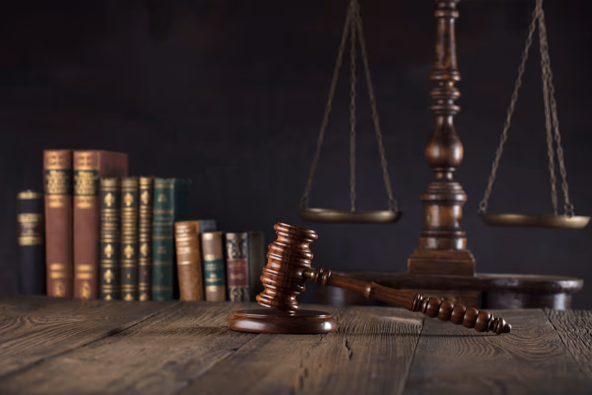 A table with a gavel, law books and scales of justice.