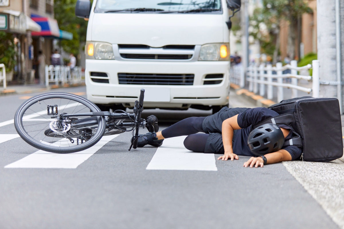Man on bike hot by car at cross walk