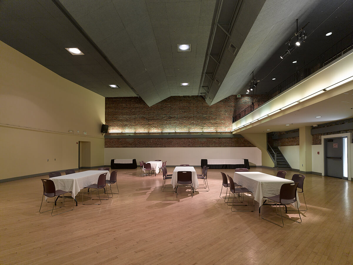 The Women’s Building auditorium arranged with tables and chairs, ready for an event or meeting.