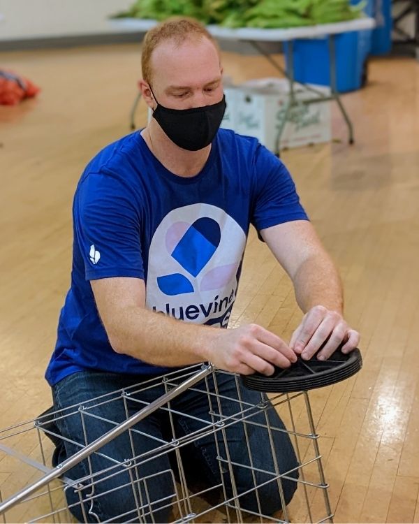 A volunteer installs part of a cart during event setup, demonstrating hands-on support for The Women’s Building.