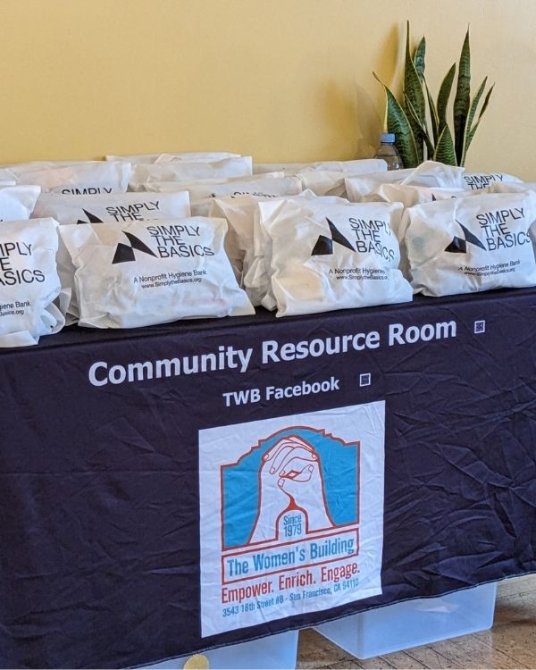 A table lined with hygiene kits labeled 'Simply the Basics' in the Community Resource Room, ready for donation to those in need.
