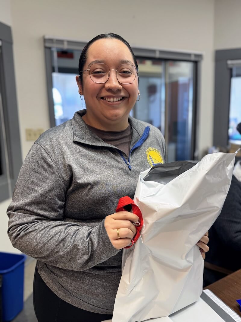 A staff member smiles while preparing a care package, part of the Post-Release Services to support migrant children and their families.