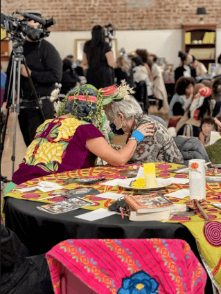 Two women in close conversation at a community gathering table.