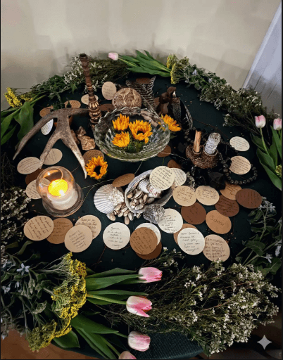Ceremonial table with flowers, candles, and handwritten messages honoring community and tradition.