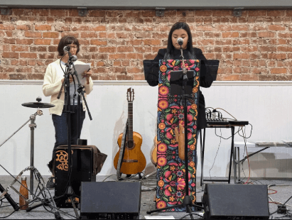 Two women speaking at a podium during a community storytelling event.