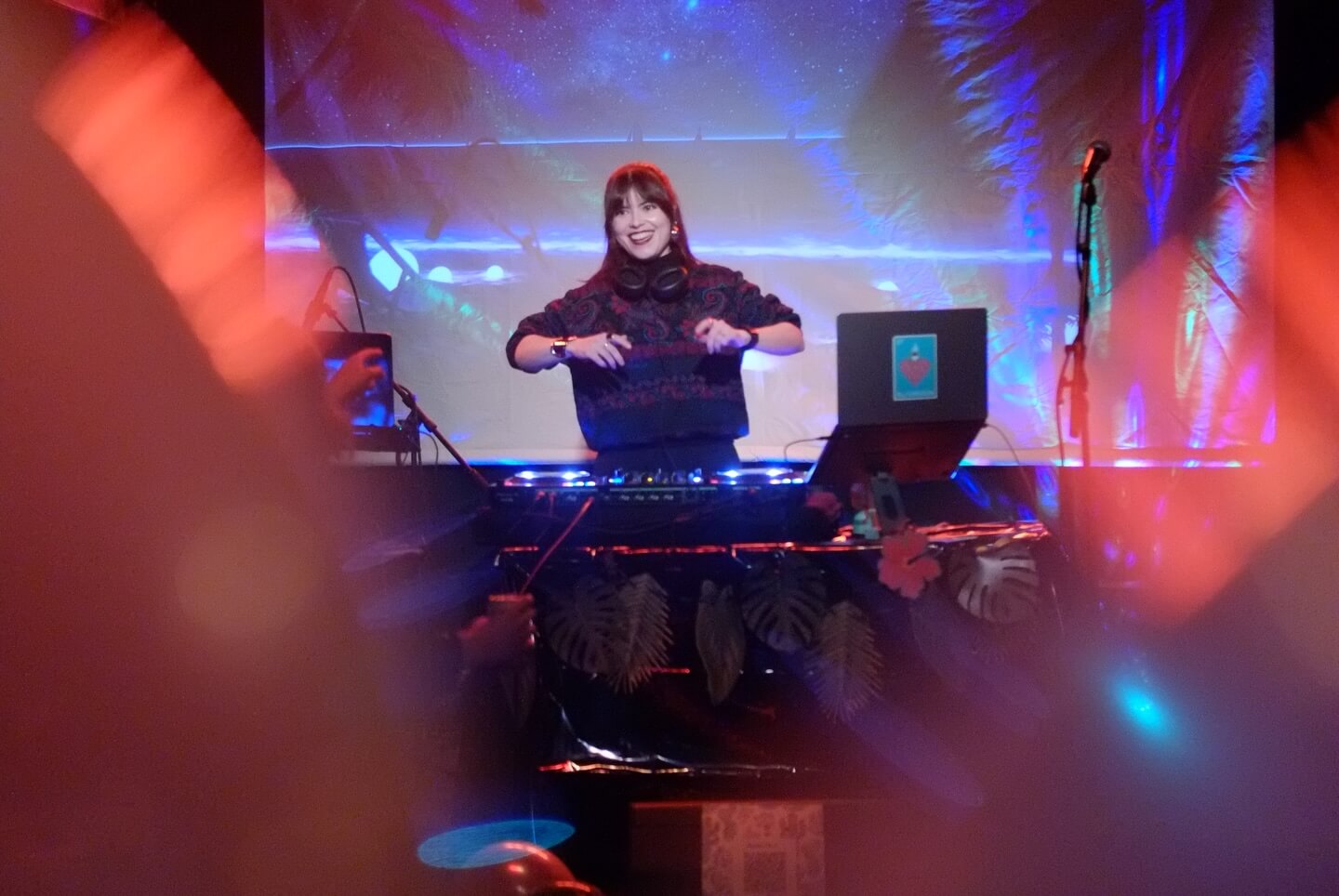 DJ Chica Múltiple performs live music set with turntables and laptop, surrounded by colorful lights during Threads of Hope event