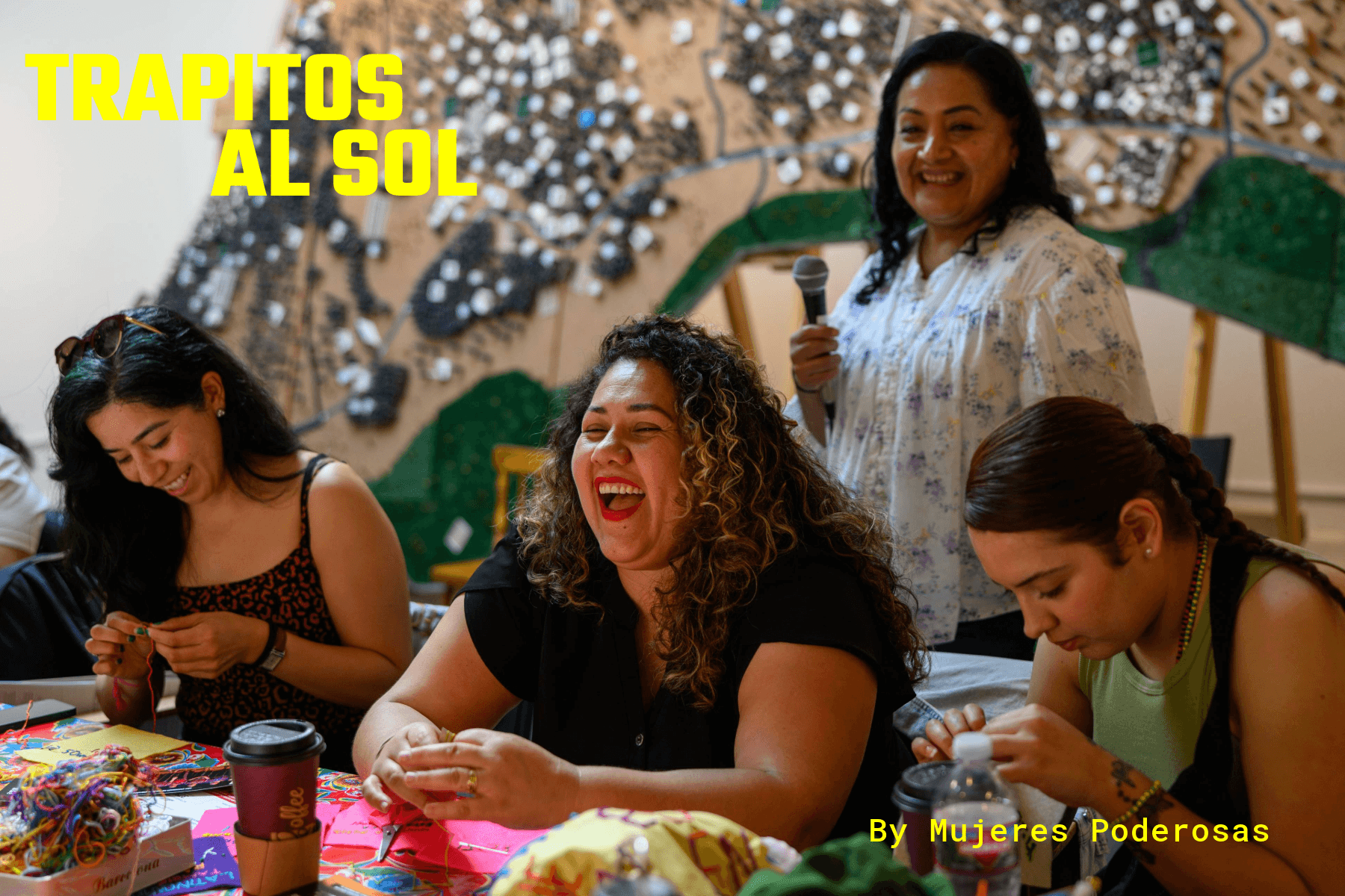 Group of women gathered around a table laughing and stitching embroidery pieces during Trapitos al Sol feminist art workshop