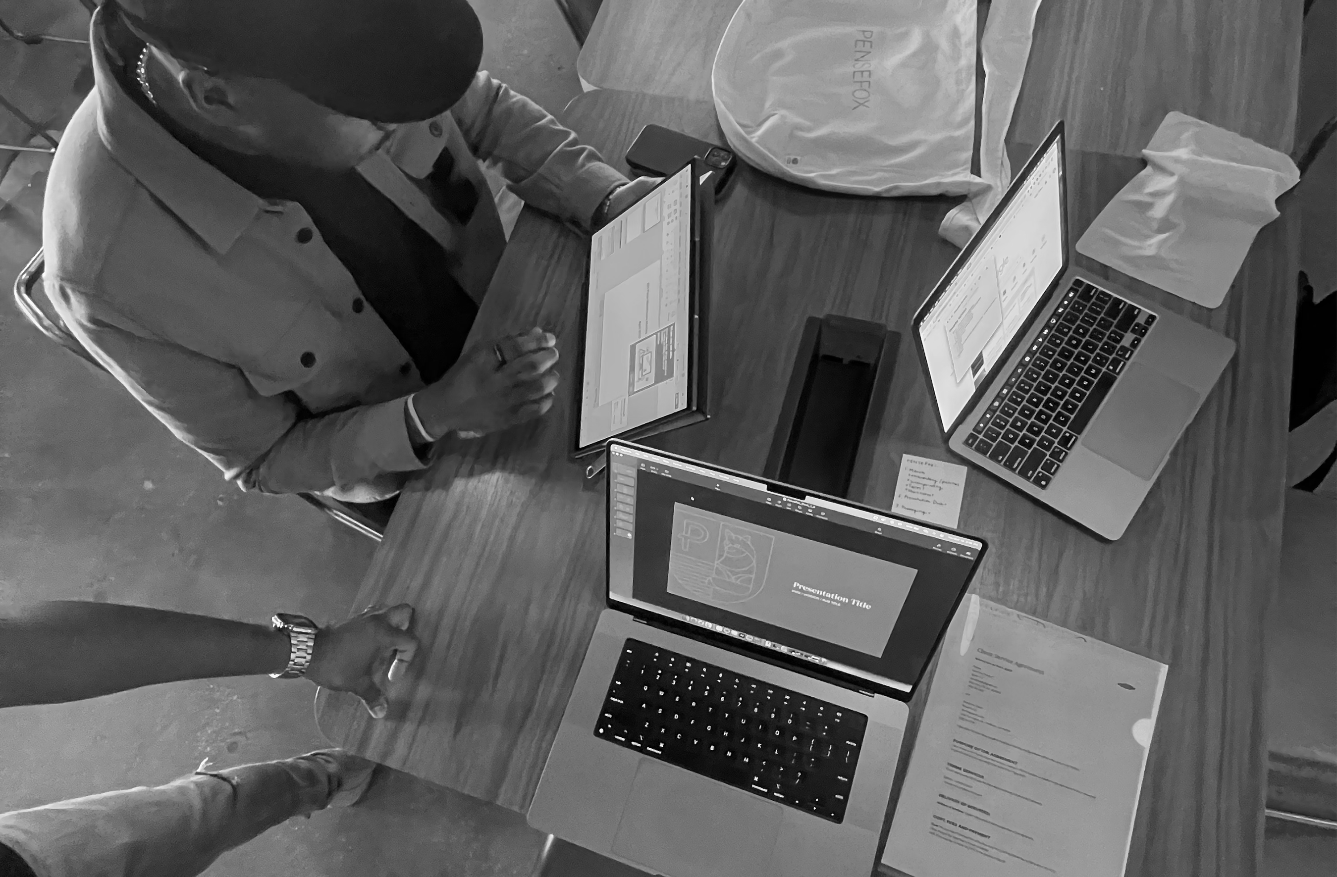 People gathered around a table with computers and tablets, looking at the screens.
