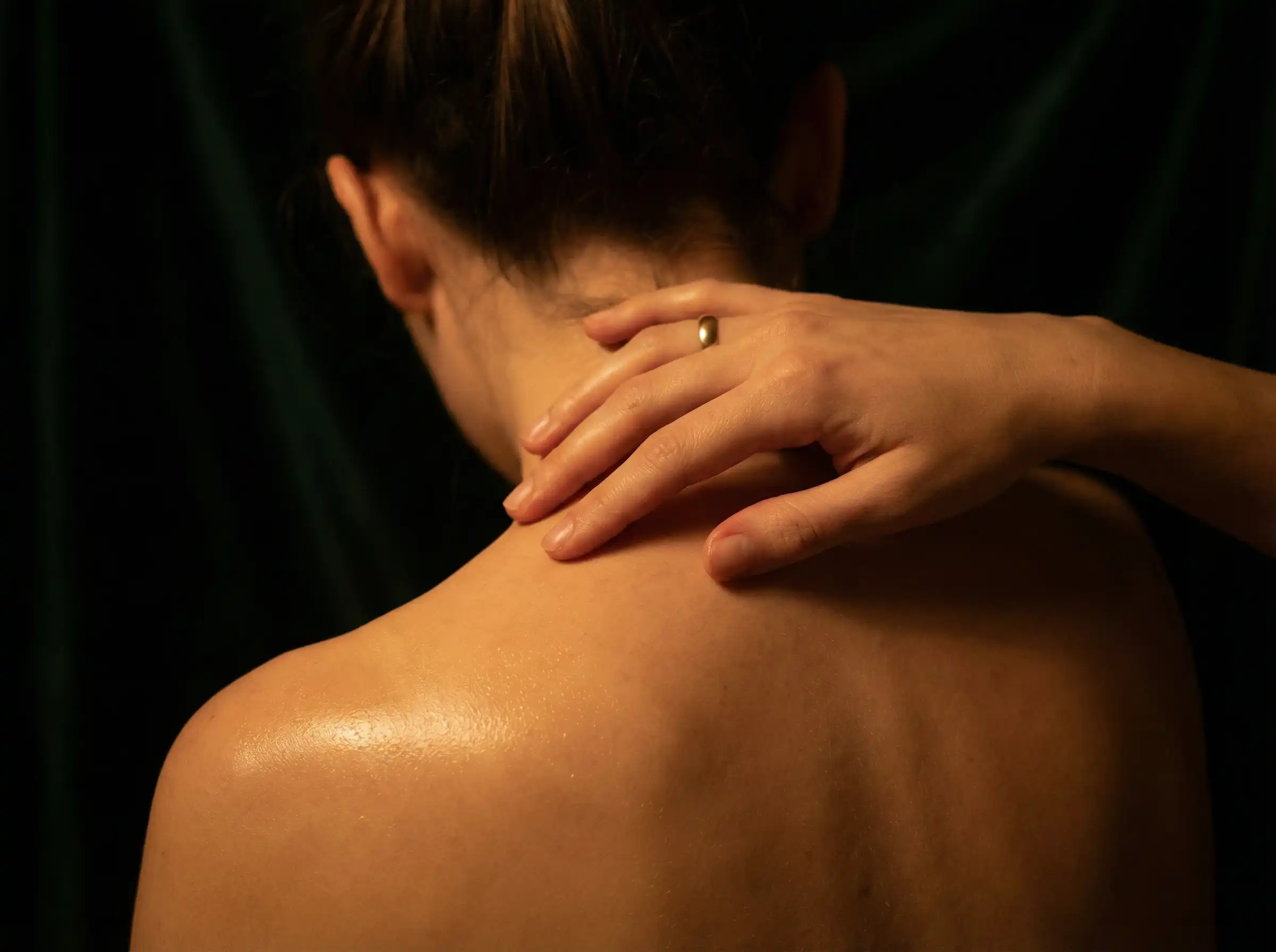 Hand auf geölter Schulter im Kerzenlicht – Massage Berührung