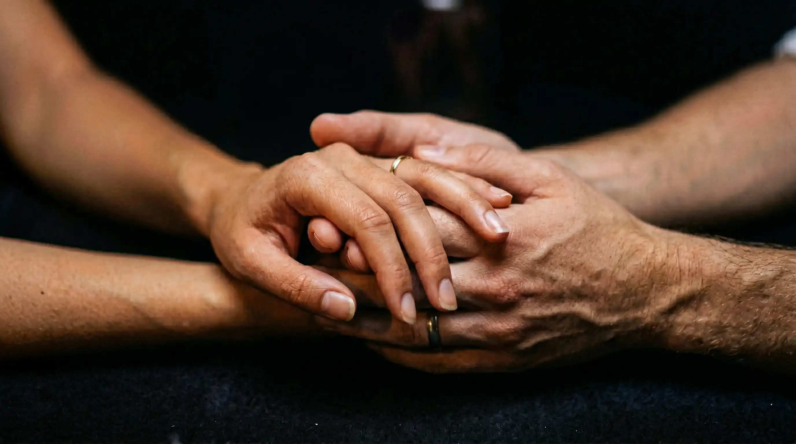 Zwei Hände die sich zärtlich berühren im Kerzenlicht