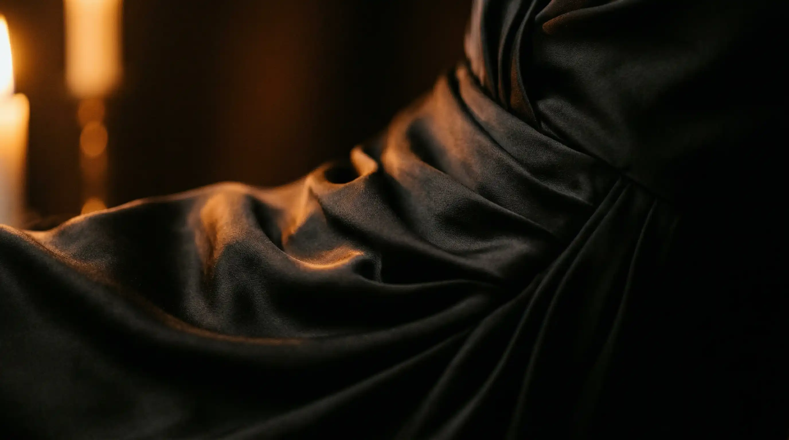 Nahaufnahme schwarzes Seidenkleid im Kerzenlicht