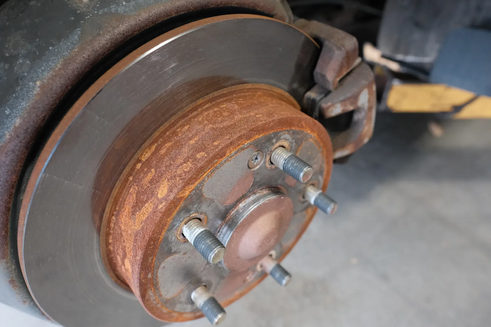 Brake rotor, caliper and wheel hub on a car raised on a lift at Granville & Avery Automotive in Marpole, Vancouver