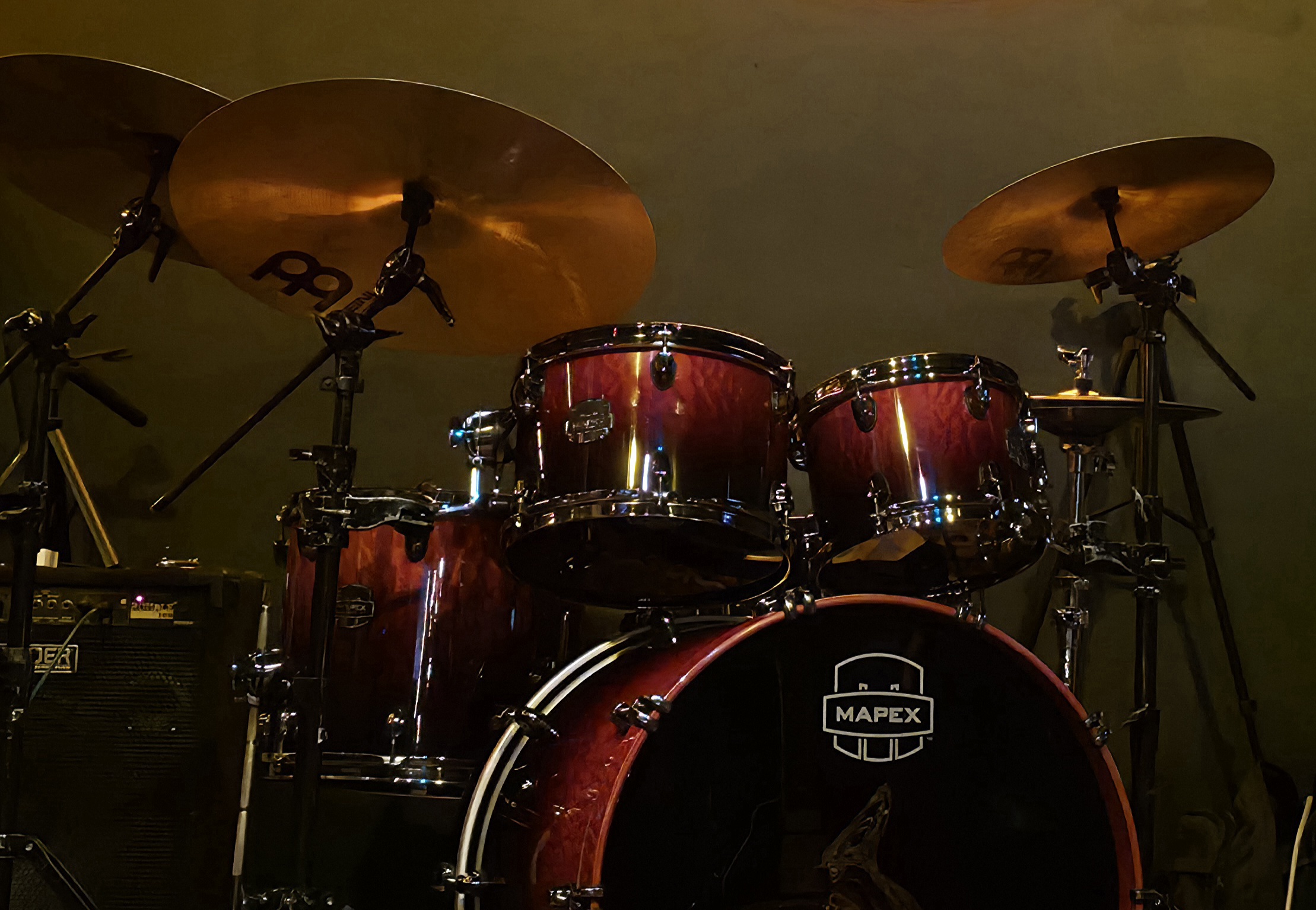 Dark red Mapex drum set with cymbals in a dimly lit room.