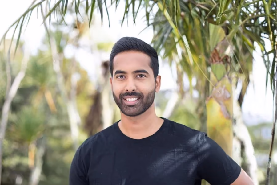 A headshot photo of a man in a dark t-shirt with short hair and a beard