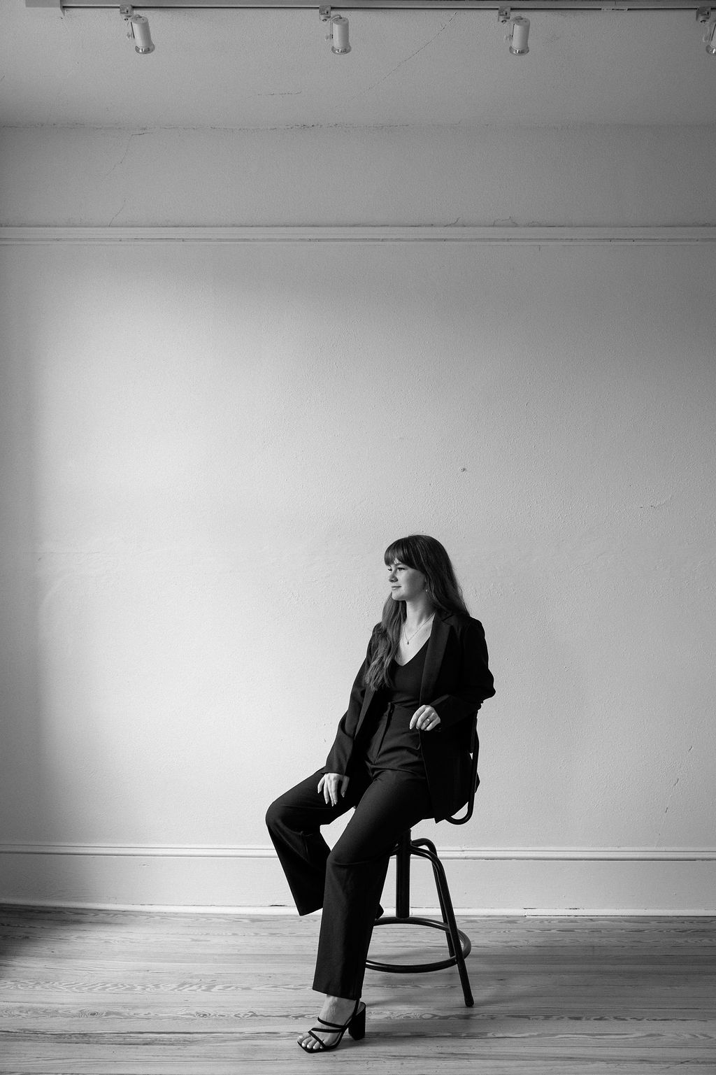 Taylor Nino, Georgia wedding planner, seated in black suit for editorial studio portrait