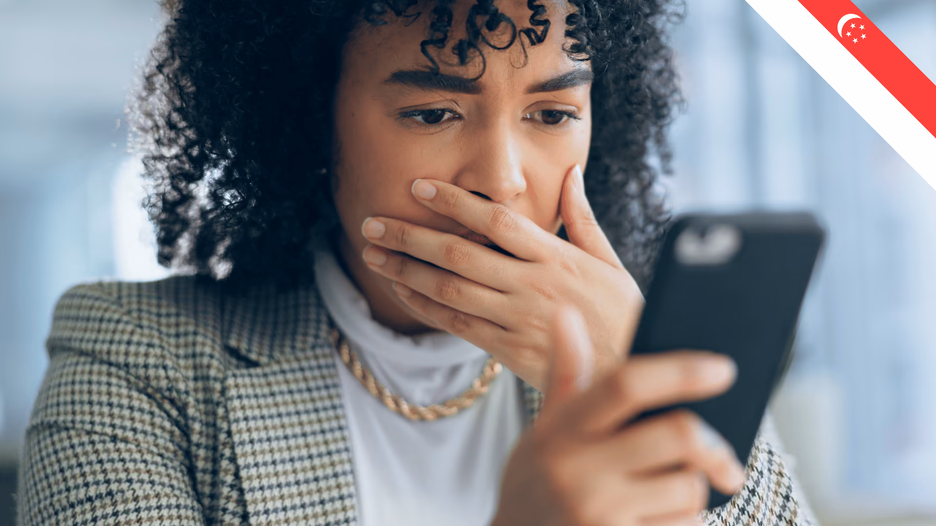 A person looking worried at their phone, possibly due to being scammed.
