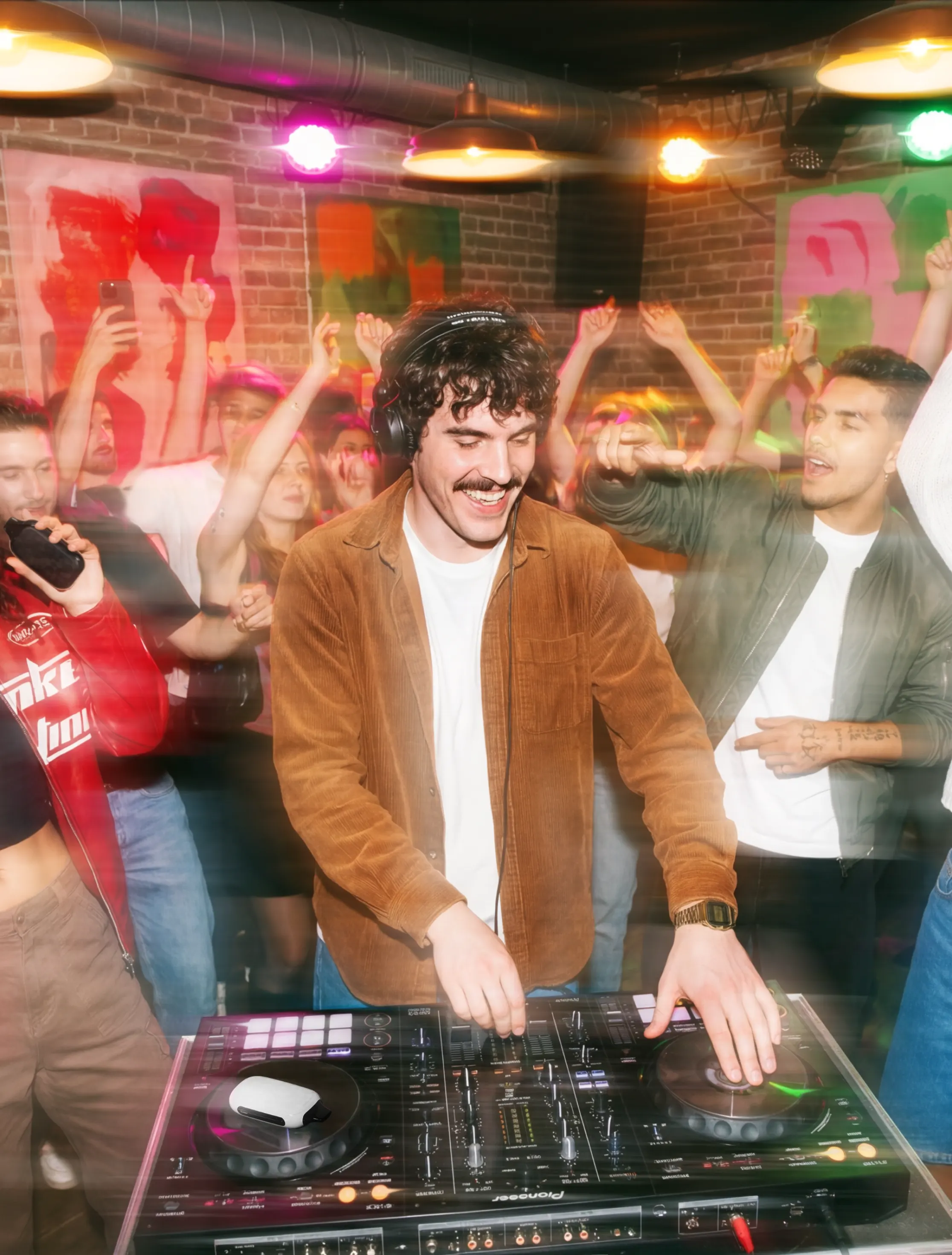 Диджей играет на пульте, окружён танцующими людьми, электронная сигарета ROQY лежит рядом с пультом