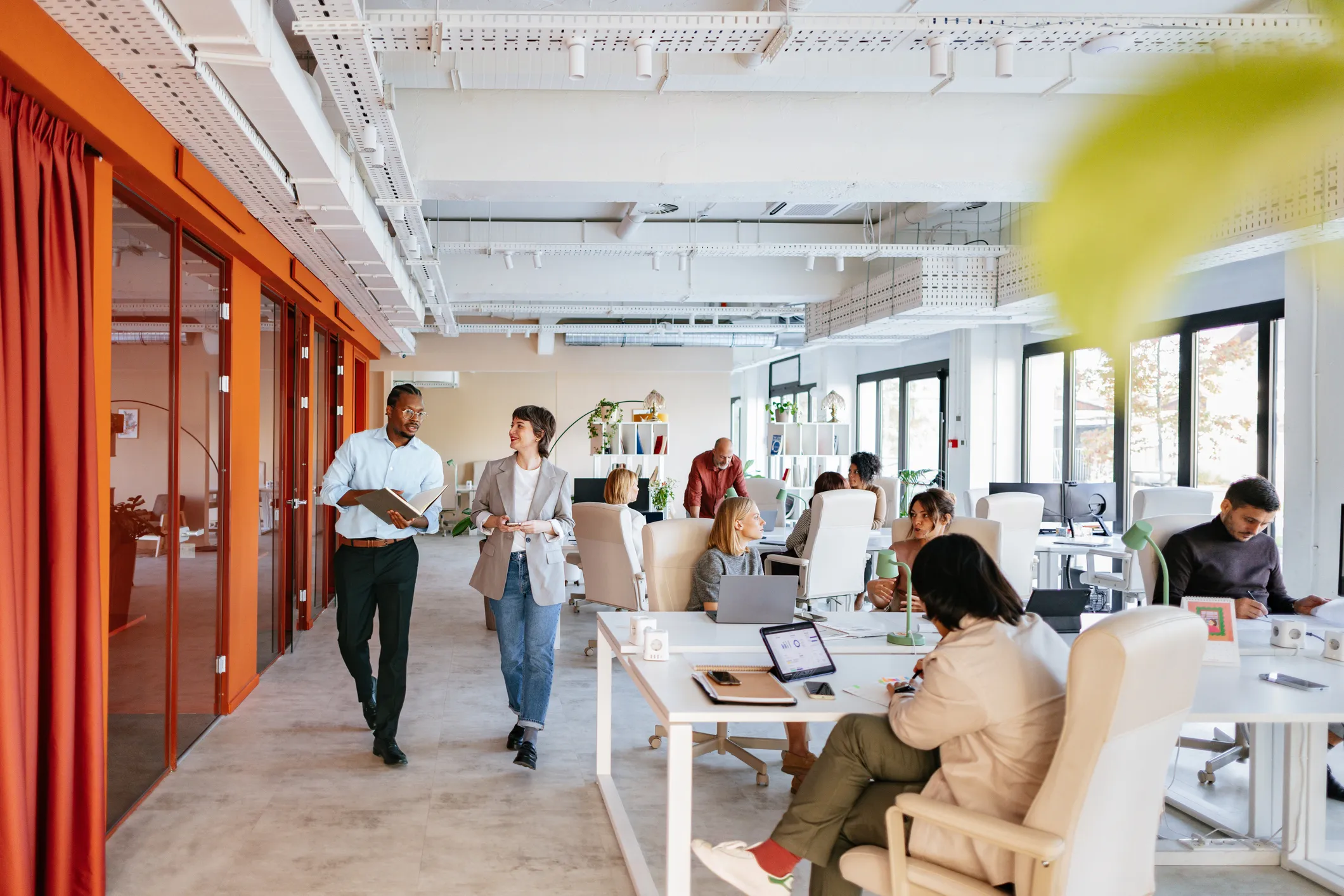 Busy, bright open-plan office with colleagues working and talking