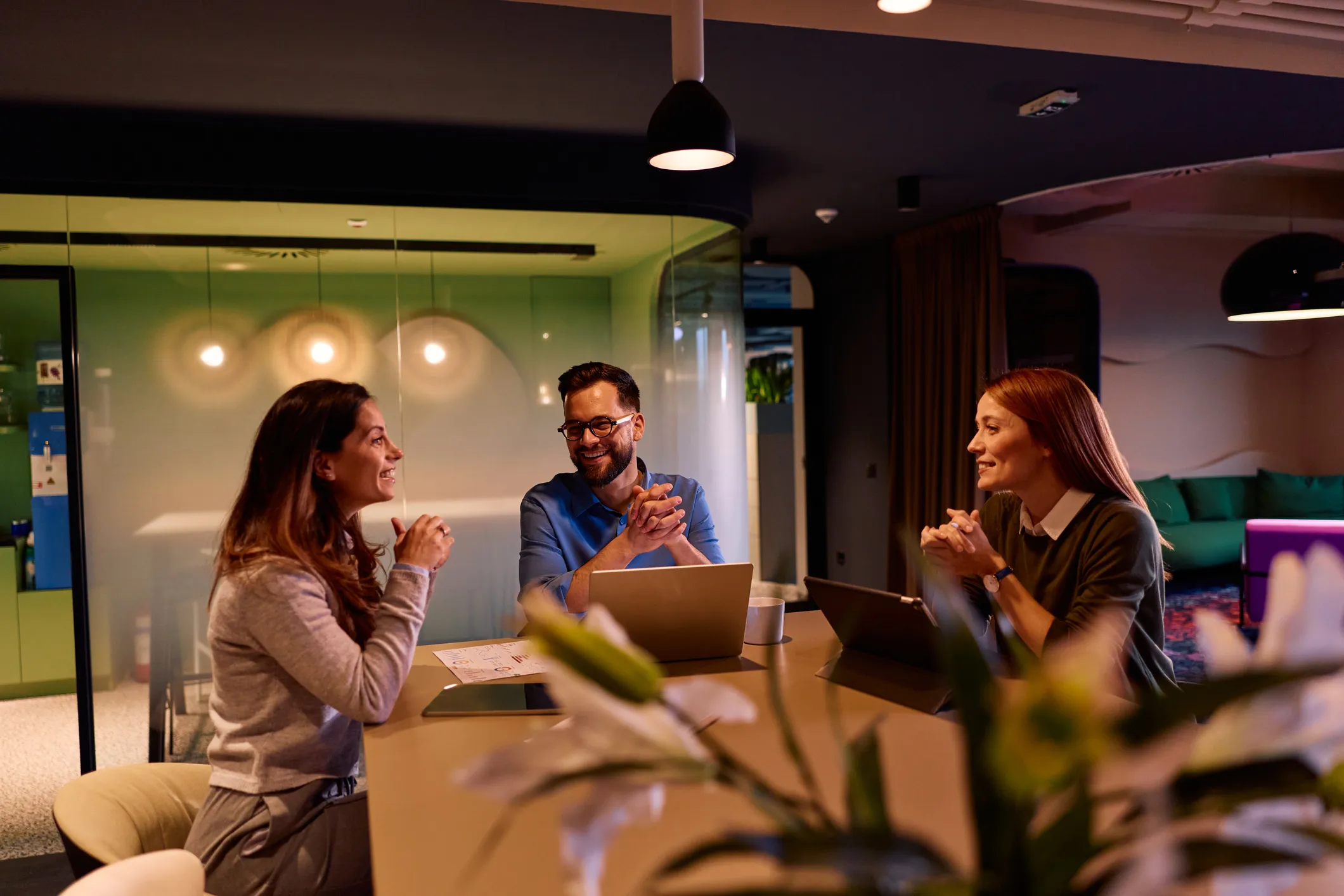 Colleagues chatting around a meeting table in a warmly lit office