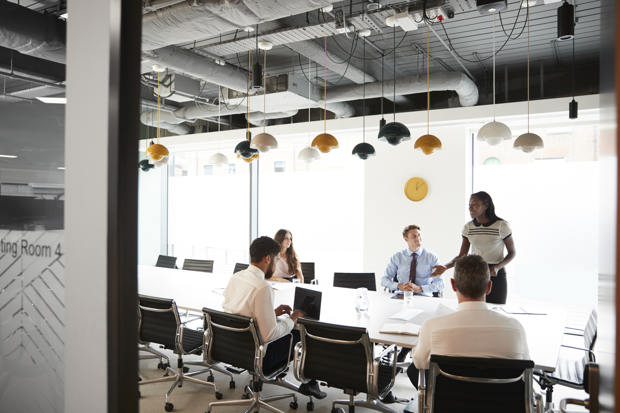 Colleagues in a team meeting around a table in a modern glass-walled meeting room