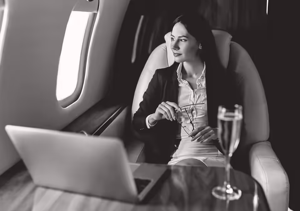 A woman sitting in an airplane looking at her laptop.