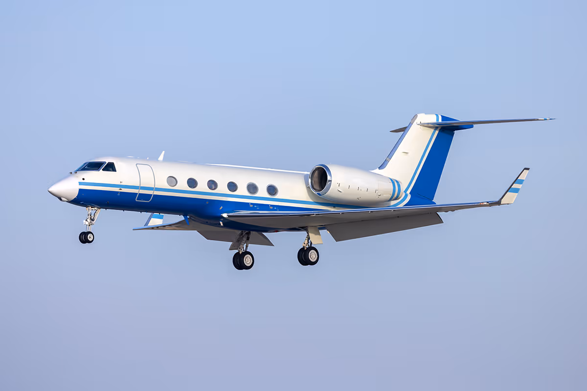 Small private jet airplane flying against a clear blue sky.