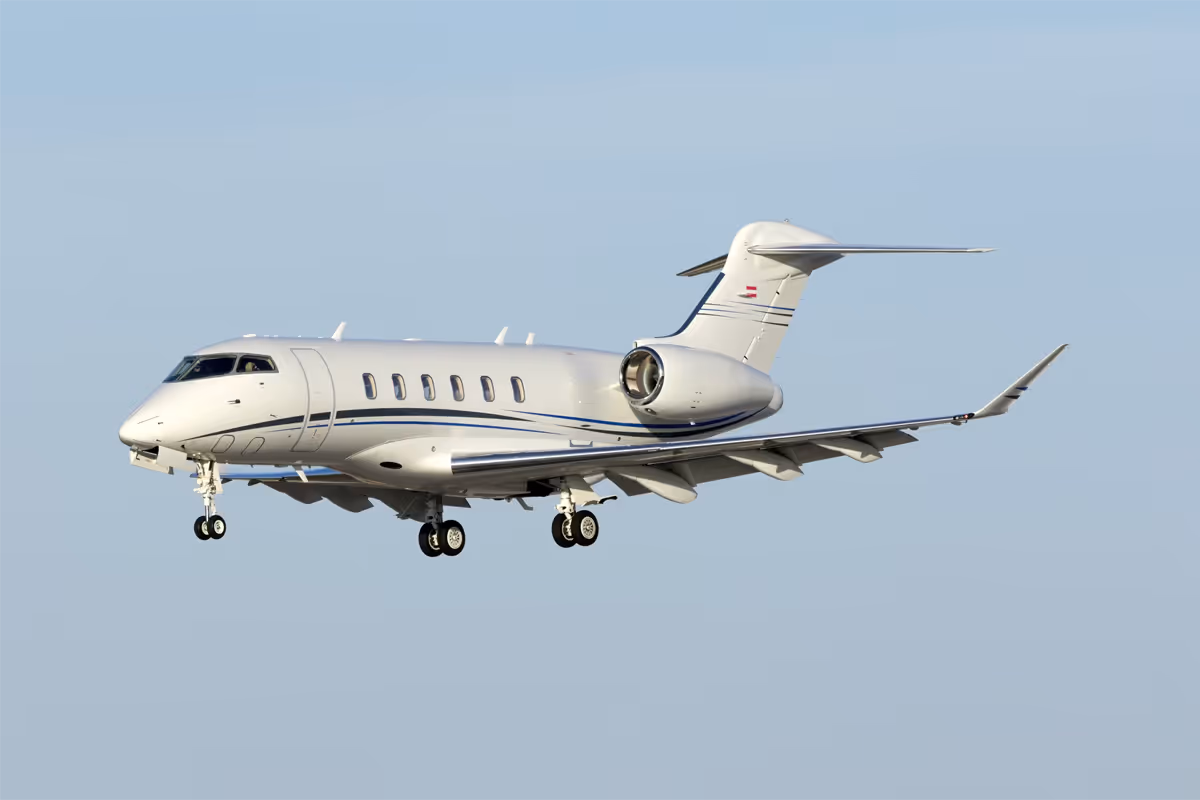White private jet airplane flying against a clear blue sky.