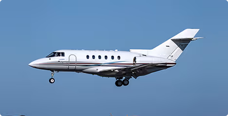 White private jet airplane flying against a clear blue sky.
