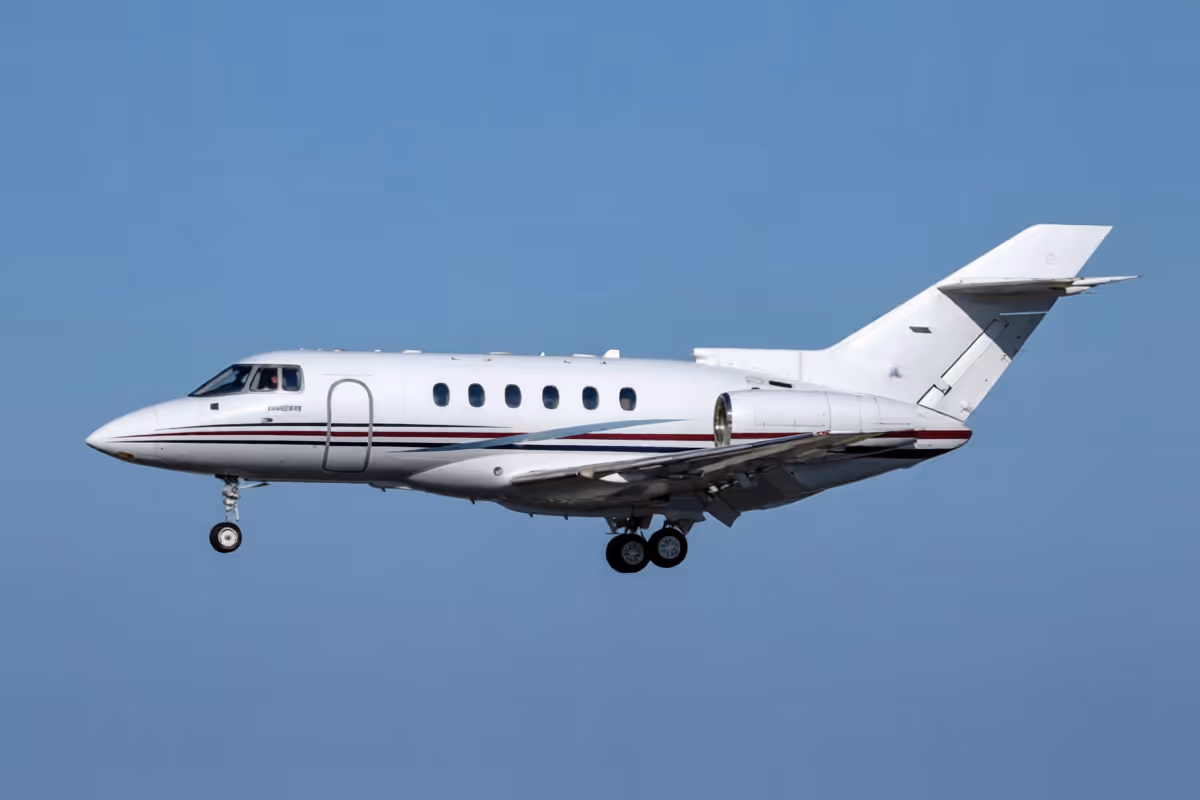 White private jet airplane flying against a clear blue sky.