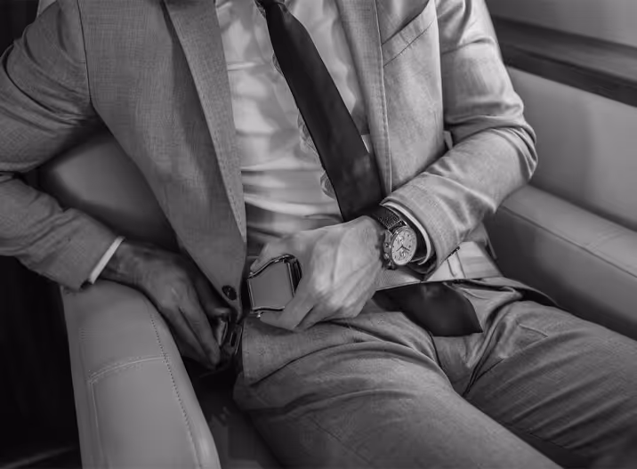 Man in a suit fastening his seatbelt while sitting in a car seat.