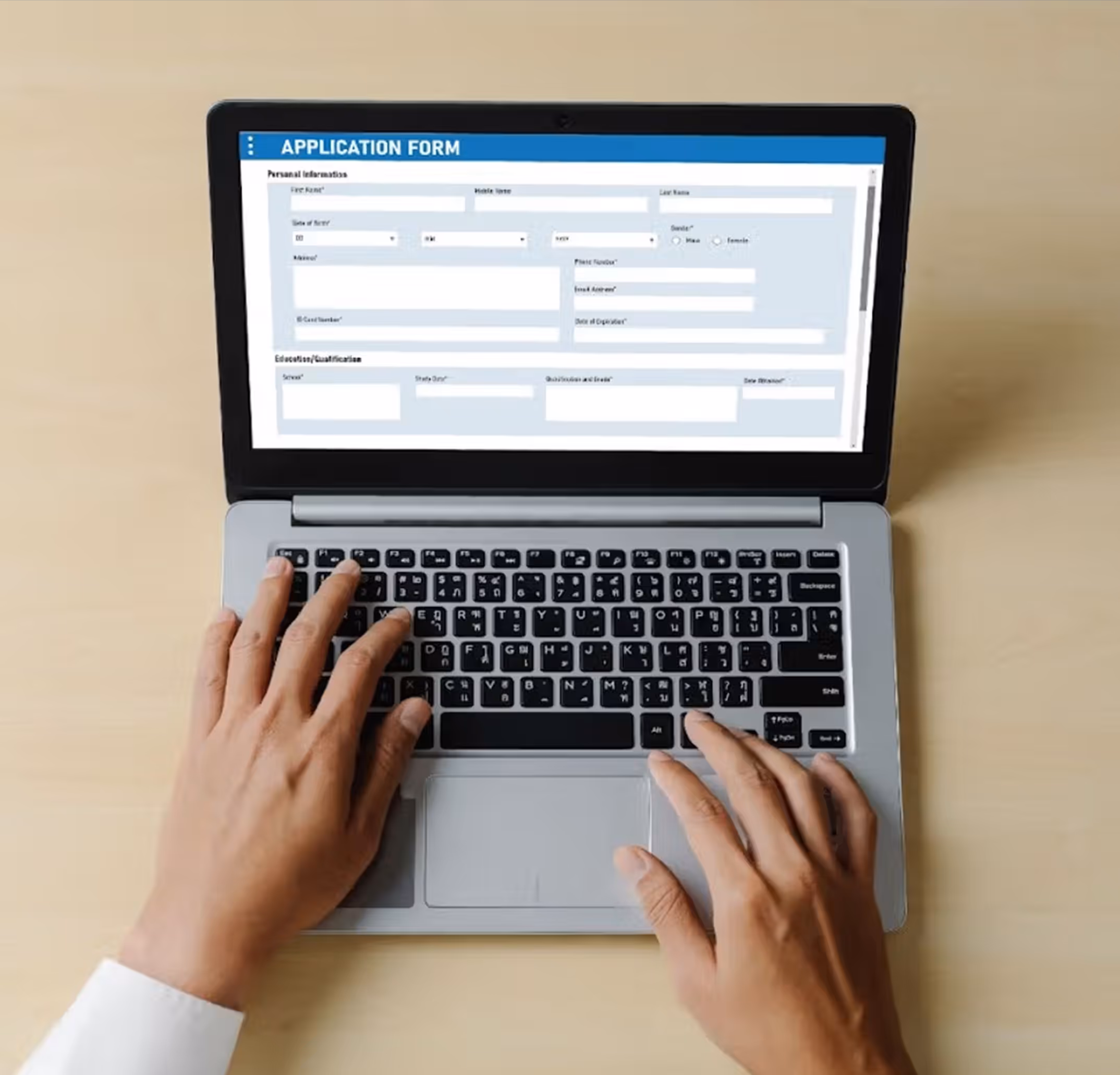 Person typing on a laptop showing an application form on the screen.