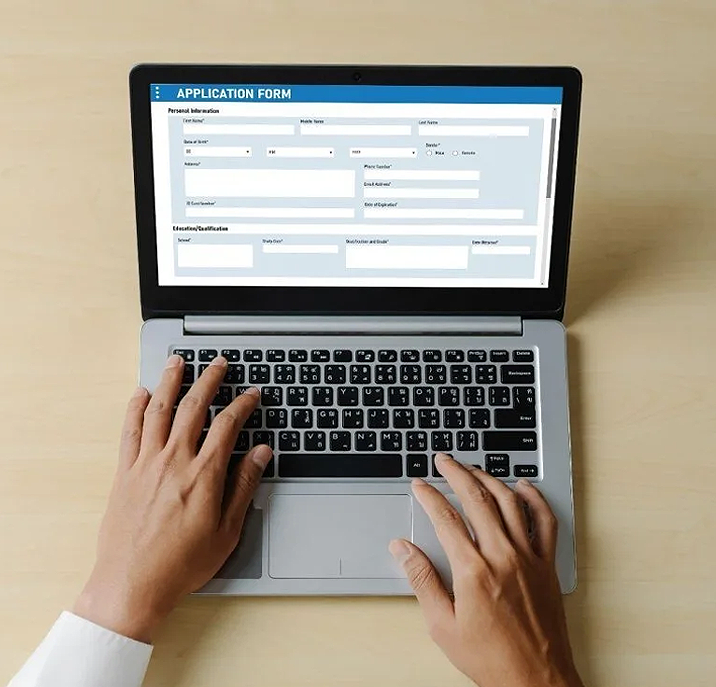 Person typing on a laptop showing an application form on the screen.