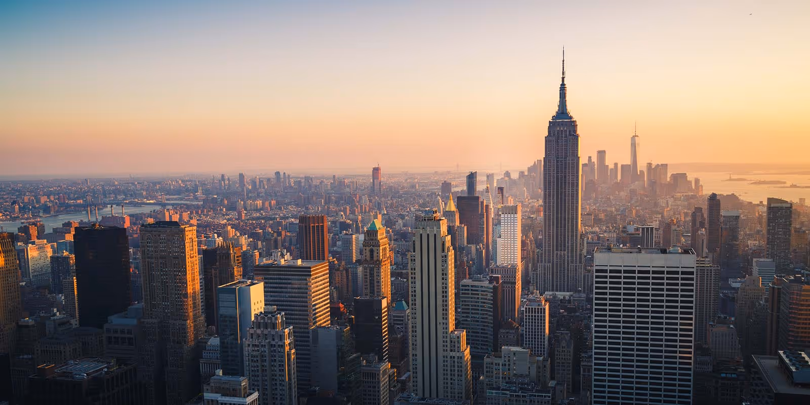 View of New York City skyline at sunset with the Empire State Building prominently in the center.