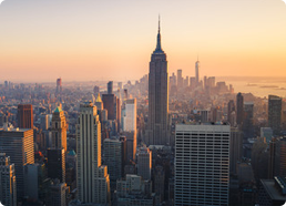 View of New York City skyline at sunset with the Empire State Building prominently in the center.