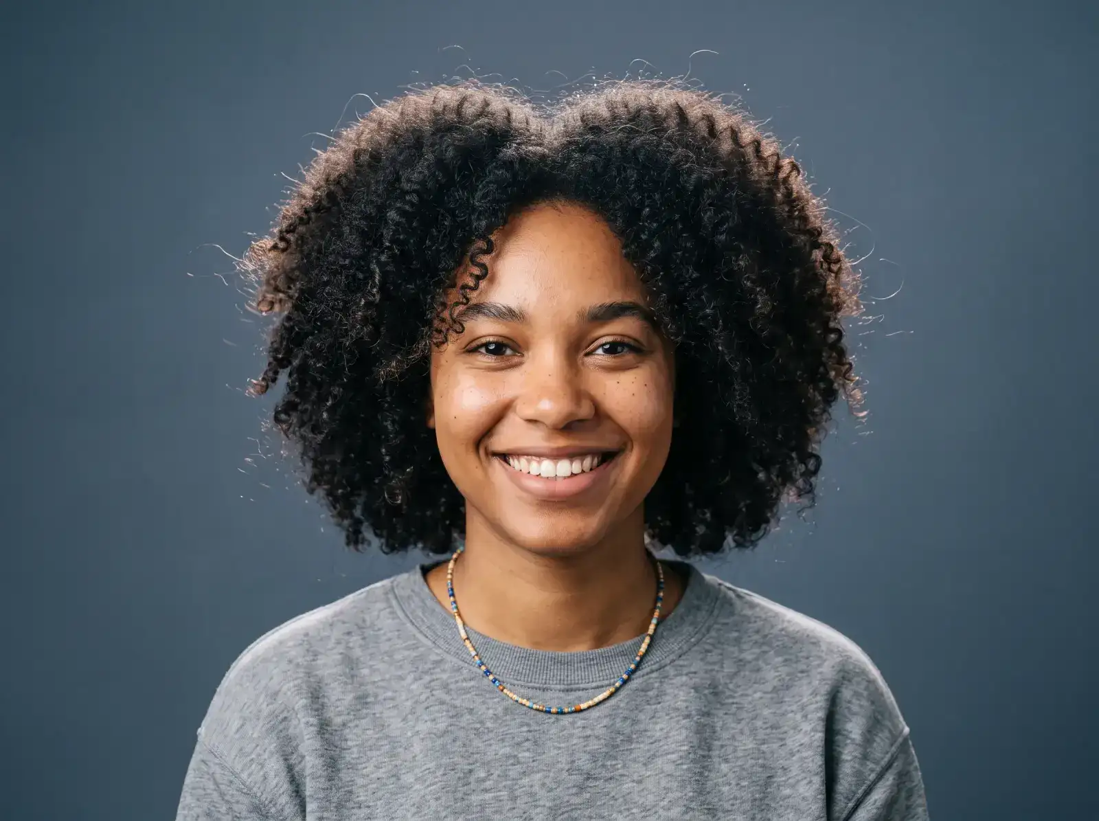 Portrait with curly hair on a blue studio background, before background removal