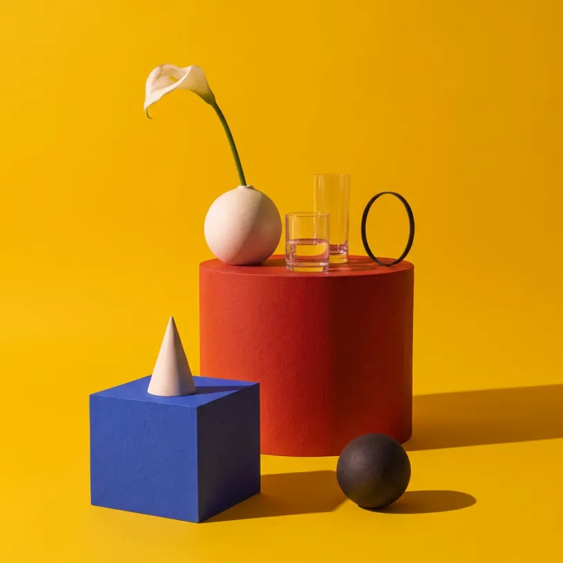 Still life with a vase, a cube and a cone on a yellow background