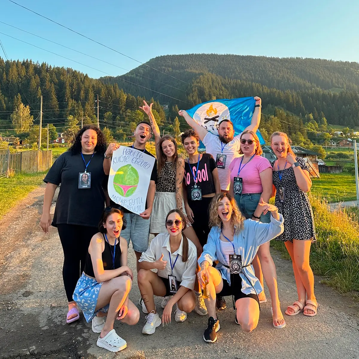 Щасливі люди у горах позують із прпором табору ватра кемп