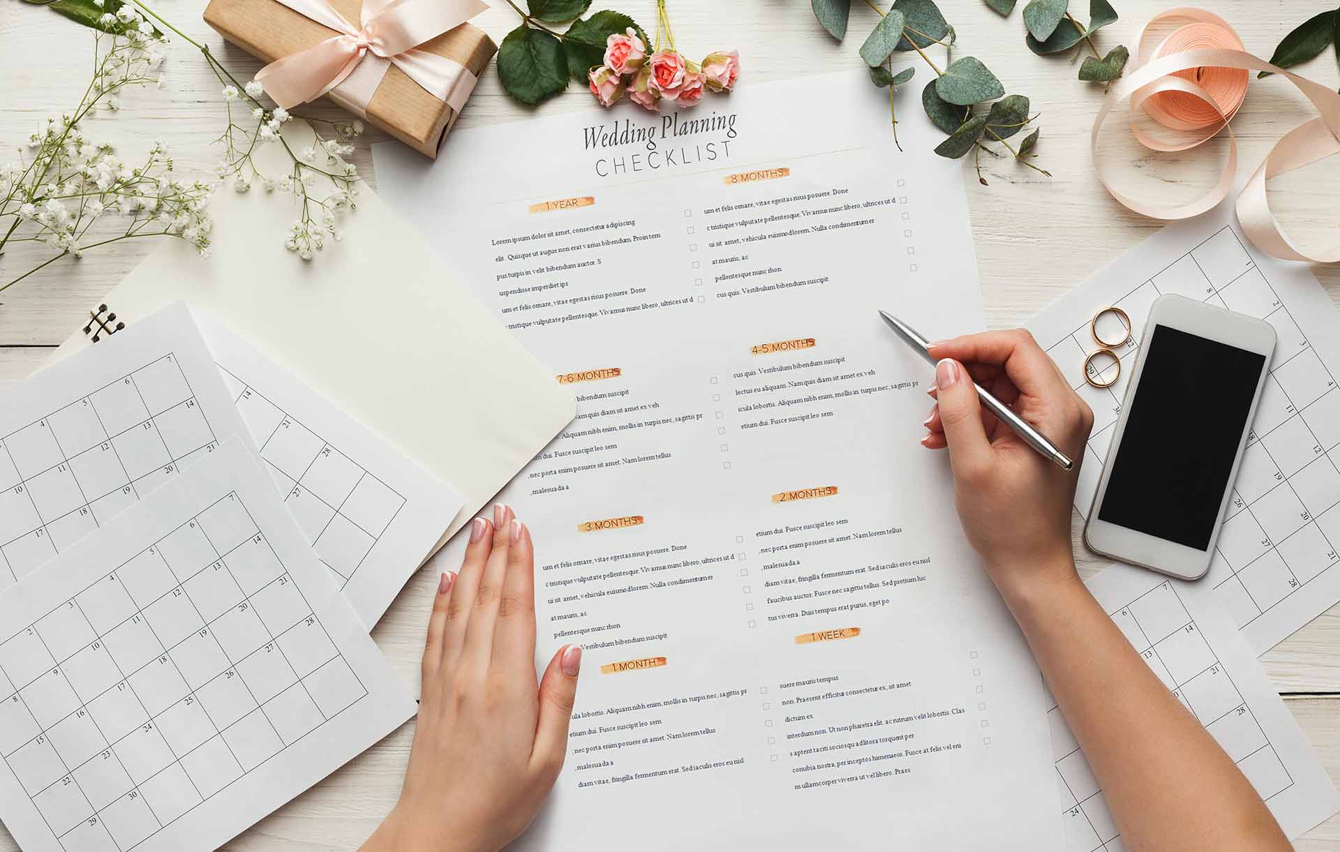 Wedding planning checklist with calendar and rings on desk