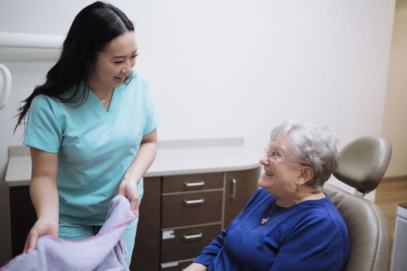 Dental professional consulting with senior patient in chair about jaw or dental concerns
