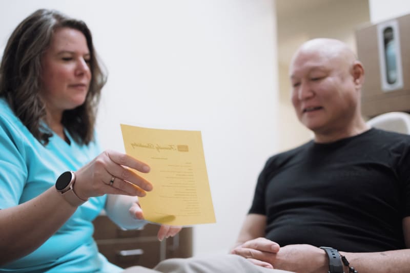 Dentist in teal scrubs reviewing yellow form with patient, explaining treatment details