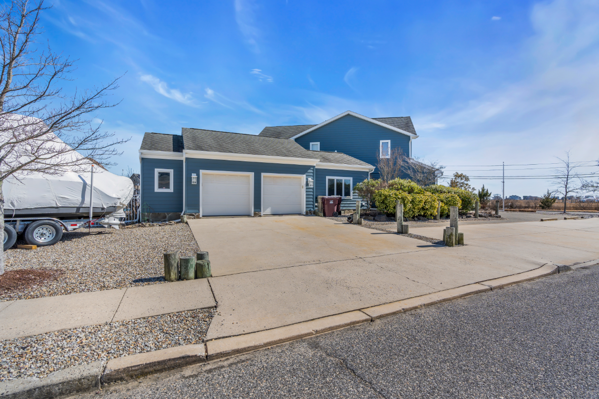 Two-car garage view of updated Bayville NJ home featuring smooth concrete driveway and decorative landscaping.