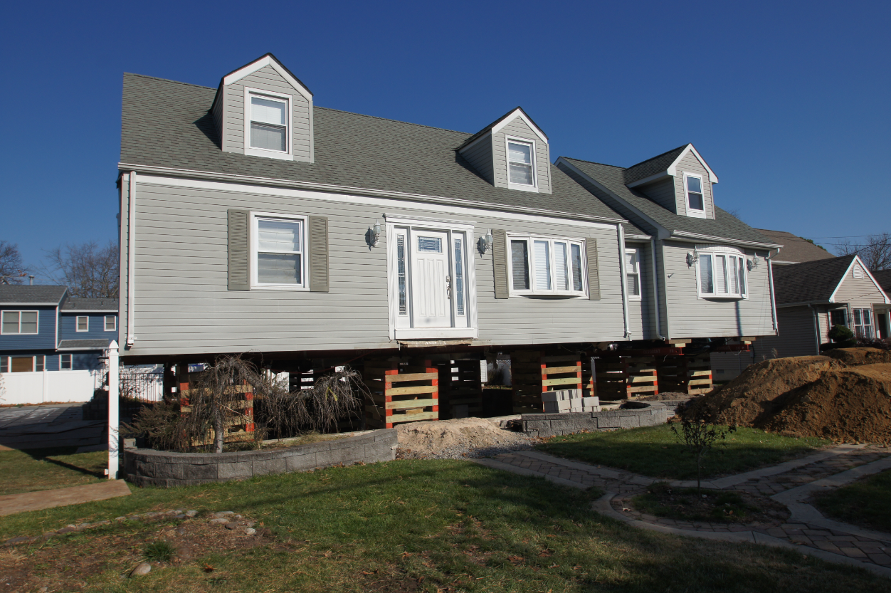 Angled view of raised home with visible stacked cribbing and foundation work underway, part of structural elevation  in Toms River NJ