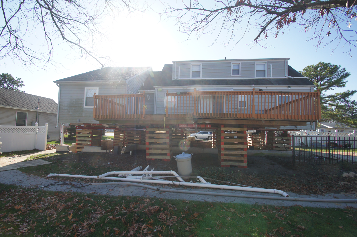 Rear deck elevated with home, supported by cribbing and temporary beams during house lift construction in Toms River NJ.