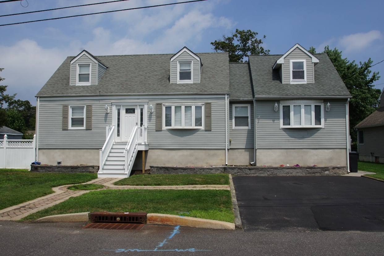 Front-facing completed photo after house lift, with new entry stairs, restored siding, and finished landscaping in Toms River NJ