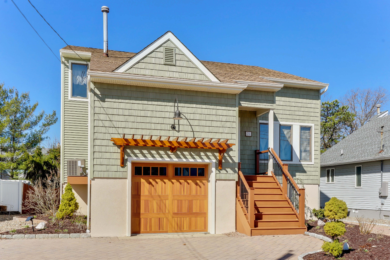 Left-side perspective of home lift project in Toms River, NJ, showing siding detail, modern stair railing, and neatly designed front yard.