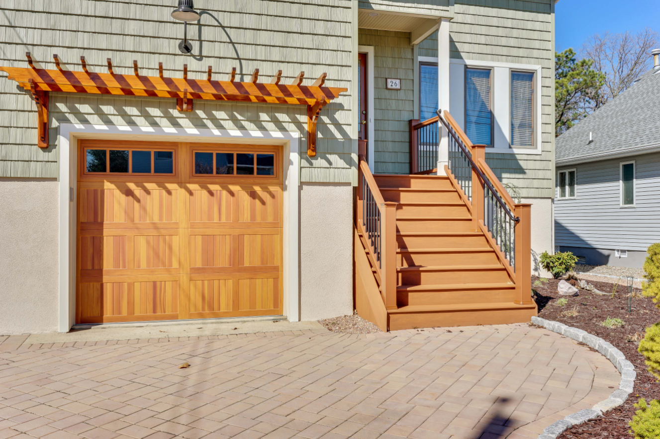 Close-up of new wood garage door and composite entry stairs with black metal railing—part of a Toms River exterior renovation.
