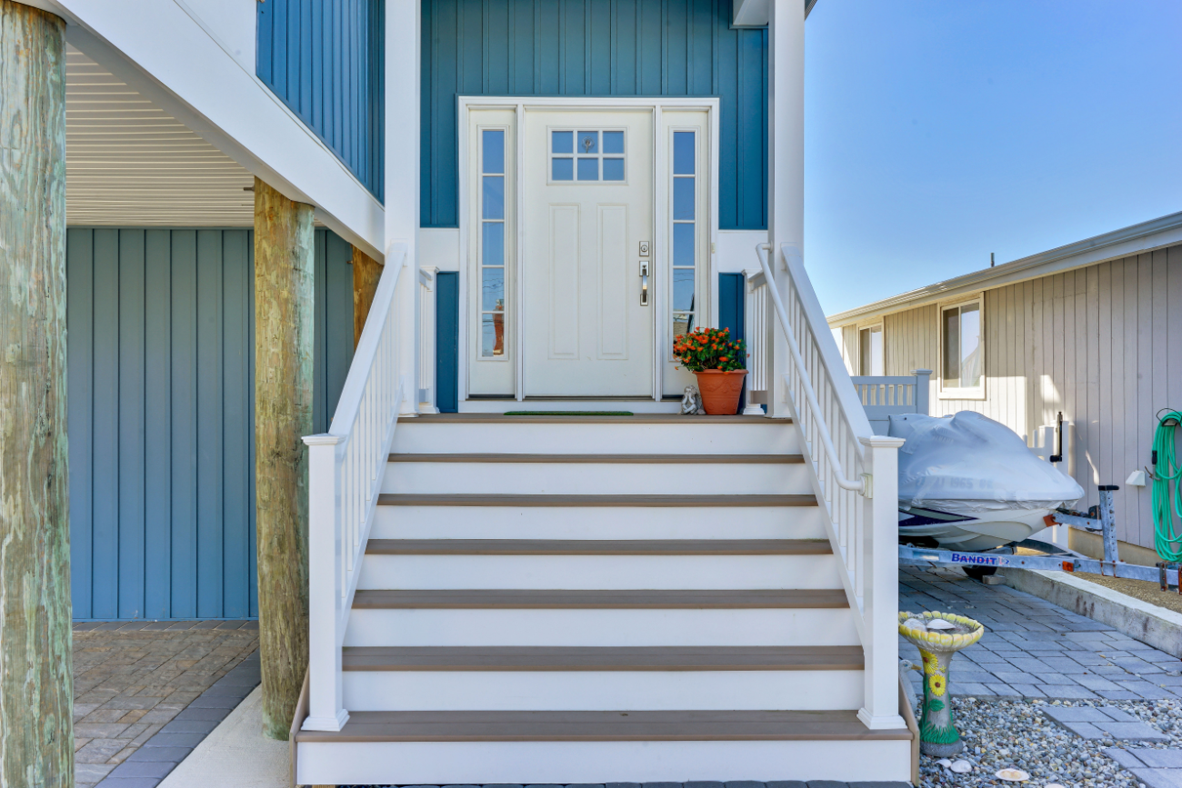 Entryway stairs and front porch with custom white railings and floral accents in coastal home built by J.A.Y. Construction