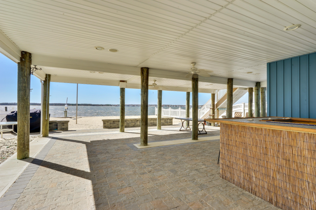 Covered outdoor entertainment area with tiki bar, recessed lighting, and panoramic river views