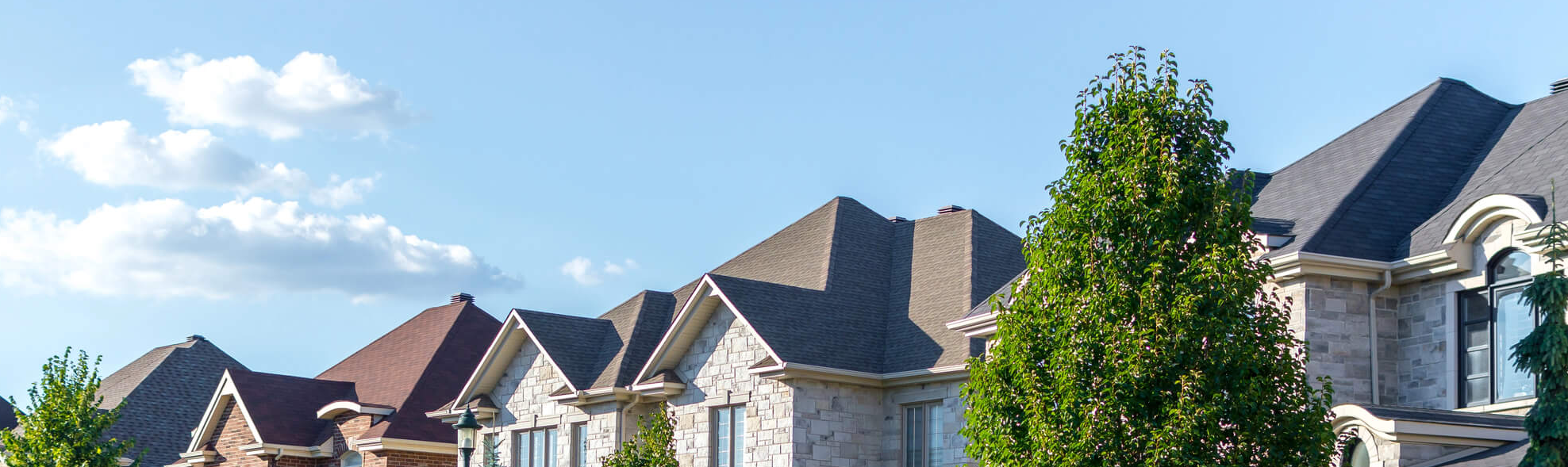 Row of upscale homes in Freehold, NJ with well-maintained shingle roofs under a blue sky. J.A.Y. Construction is the trusted expert for roofing and siding solutions.