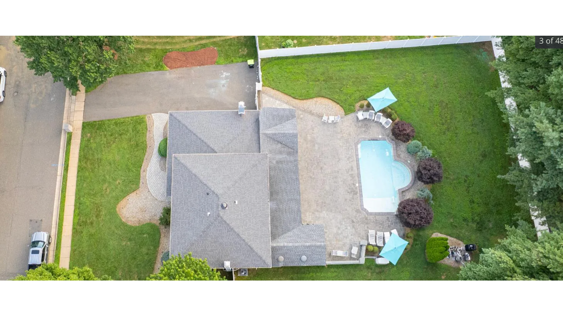 Aerial view of a Marlboro, NJ home with a gray shingle roof, spacious patio, in-ground pool, and landscaped yard. J.A.Y. Construction is a trusted name in roofing and exterior renovations in Monmouth County.